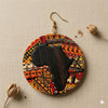 A circular, Africa-shaped earring featuring a Kente print design with a silhouette of the African continent in black.

